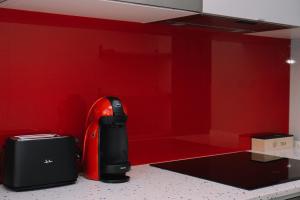 a kitchen with a red wall and a appliance at Acogedora y cálida en el centro by CABANA Rentals in Redondela