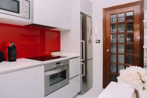 a kitchen with white counters and a red wall at Acogedora y cálida en el centro by CABANA Rentals in Redondela +23 photos