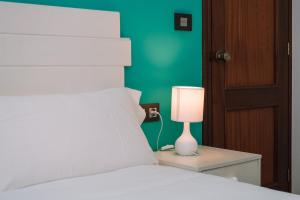 a bedroom with a bed with a lamp on a night stand at Acogedora y cálida en el centro by CABANA Rentals in Redondela