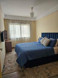a bedroom with a blue bed and a window at Appartement avec piscine in Essaouira