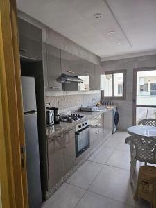 a kitchen with stainless steel appliances and a table at Appartement avec piscine in Essaouira +22 photos