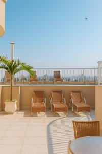 a balcony with chairs and a table and a palm tree at Green Hotéis in Cabo Frio