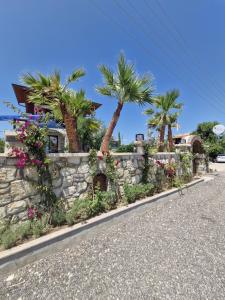 a stone retaining wall with palm trees and flowers at Velder House Urla in Urla