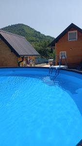 a large blue swimming pool next to a house at Sun-Moon Apartment in Zbilje