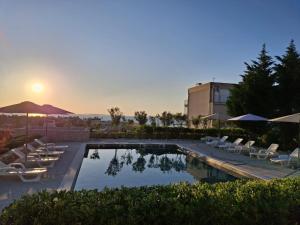 a swimming pool with chairs and the sunset in the background at Blauer Horizont in Povljana
