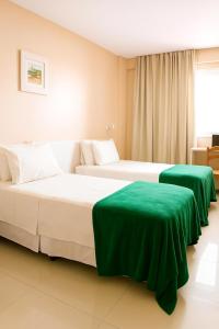 two beds with green sheets in a hotel room at Green Hotéis in Cabo Frio +29 photos