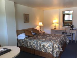 a bedroom with a bed and a desk and a table at Motel Du Chevalier in Gatineau