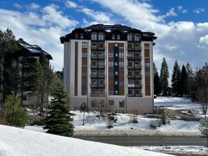 Un gran edificio con nieve delante. en Omorika Lux, en Zlatibor