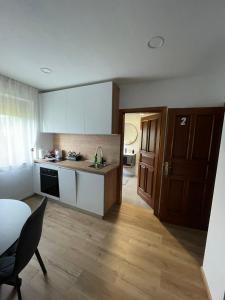a kitchen with white cabinets and a table and a chair at Studio apartman SALOPEK 2 in Ogulin