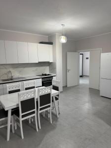 a kitchen with white cabinets and a table and chairs at Gray & White Escape - Shkoder in Shkodër