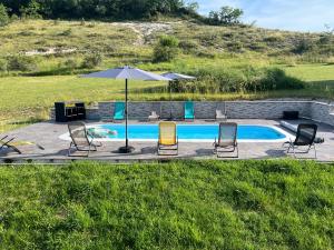 a group of chairs and an umbrella next to a pool at Chambres d'hôtes Le Malbouyssou in Lascabanes