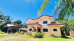 a yellow house with a palm tree at Chateau La Princesa rooms with garden, Bar & billiard in Puerto Princesa City