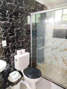 a bathroom with a toilet and a glass shower at JL Temporadas - Apto Village Taperapuan in Porto Seguro