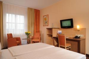 a hotel room with a bed and a desk and a television at PLAZA INN Berlin Charlottenburg in Berlin