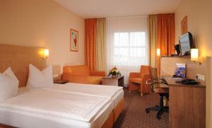 a hotel room with a large white bed and a desk at AMBER ECONTEL Berlin Charlottenburg in Berlin