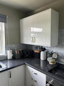 eine Küche mit weißen Schränken und einer schwarzen Arbeitsplatte in der Unterkunft Rosemount Apartment in Shildon
