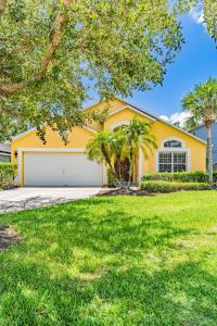 a yellow house with palm trees in front of it at Allamanda at White Rose Villas in Kissimmee