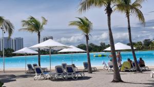a beach with chairs and palm trees and a pool at Apartmento en Playa Blanca Rio Hato in Río Hato