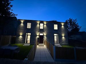 a brick house with lights on it at night at Luxury Sovereign House in Brighouse