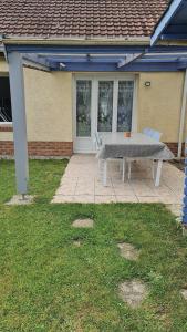 a picnic table and two chairs in front of a house at Maison plein pied à Quend in Quend