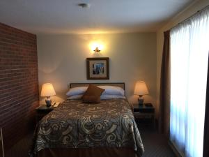 a bedroom with a bed with two lamps and a window at Motel Du Chevalier in Gatineau