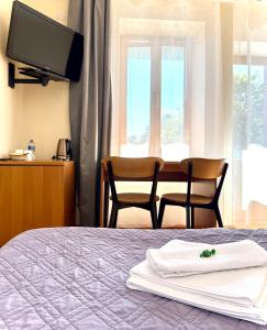 a bedroom with a bed with two chairs and a television at Akmuo Ant Akmens in Šventoji