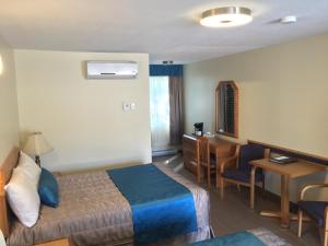 a hotel room with a bed and a desk at Motel Du Chevalier in Gatineau