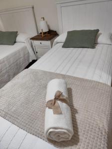two white beds with a towel on top of them at Viña da Igrexa, casa con jardin y barbacoa en cambados in Cambados