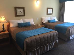 a hotel room with two beds with blue sheets at Motel Du Chevalier in Gatineau