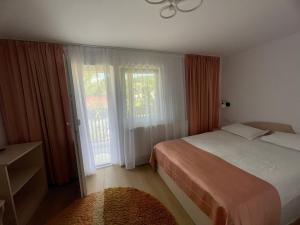 a bedroom with a bed and a large window at Pensiunea Antonia in Vatra Dornei