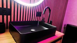 ein Badezimmer mit einem schwarzen Waschbecken und einer rosa Wand in der Unterkunft Propiedad San Salvador in Mogán