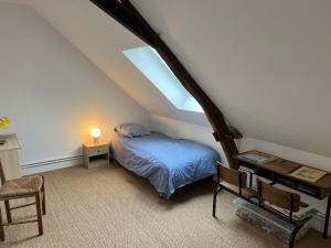 a attic bedroom with a bed and a window at Charmant corps de ferme réhabilité en Mayenne in Daon