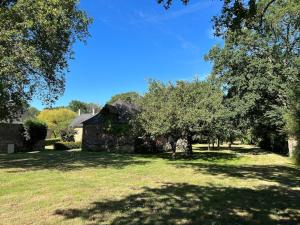 an old stone house in a field with trees at Charmant corps de ferme réhabilité en Mayenne in Daon
