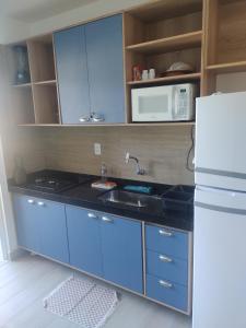 a kitchen with blue cabinets and a sink and a refrigerator at Flat Flecheiras in Trairi