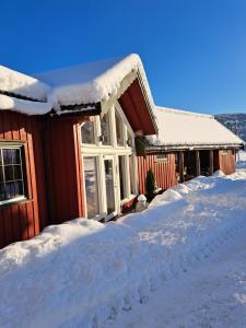 a house covered in snow with a pile of snow at Torvløbakkan Gard in Kvinesdal