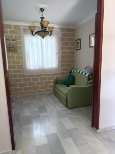 ein Wohnzimmer mit einem grünen Sofa und einem Fenster in der Unterkunft Casa Coplas muy cerca de la playa in Sanlúcar de Barrameda + 13 Fotos