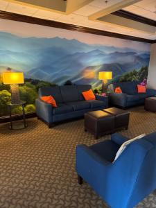 a living room with blue couches and a painting on the wall at Vista Suites Near Island and Leconte Convention Center in Pigeon Forge