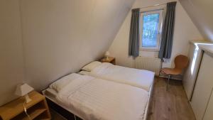a small bedroom with a bed and a window at Bosvilla in Harfsen