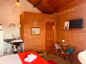 a room with a bed and a table and a television at Chalé Caminho das Flores in Santo Antônio do Pinhal
