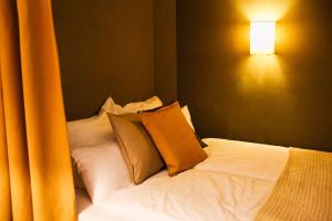 a bed with two pillows and a light on the wall at stilvoll, gemütlich und ruhig - Bad Kösen - salt apartments in Naumburg
