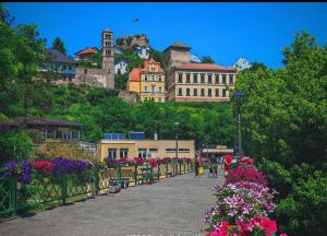 a walkway with flowers and buildings on a hill at Cottage MIRNI RAJ in Jajce