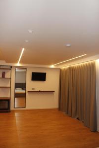 a room with a curtain and a flat screen tv at Vironas Hotel in Himare