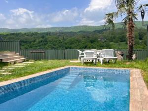 a swimming pool with two chairs and a table at Quba Harmoniya in Quba
