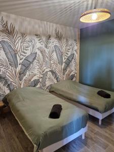 a bedroom with two beds and a wall with a wallpaper at Le Petit Rivière in Berny-Rivière