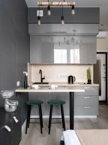 a kitchen with a sink and two green bar stools at The Stay Hub in Kyiv
