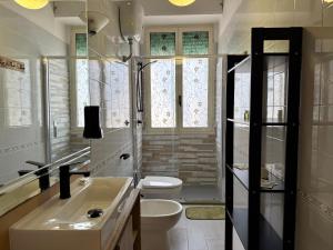 a white bathroom with a toilet and a sink at RM's Guesthouse in Brindisi +3 photos