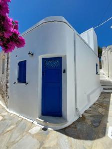 a white building with a blue door on it at Michalis little sunrise in Mamádhos