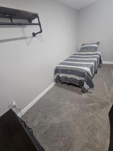 a bed with a striped blanket in a white room at Welcome in Woodlawn