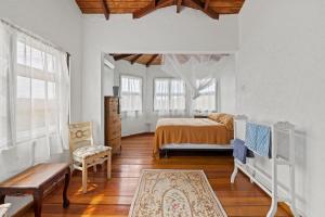 ein Schlafzimmer mit einem Bett und einem Stuhl in einem Zimmer in der Unterkunft Charming Private Cottage in Gated Estate in Belmont + 31 Fotos