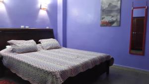 a bedroom with a bed with a purple wall at Hotel la brise in Aïn El Turk